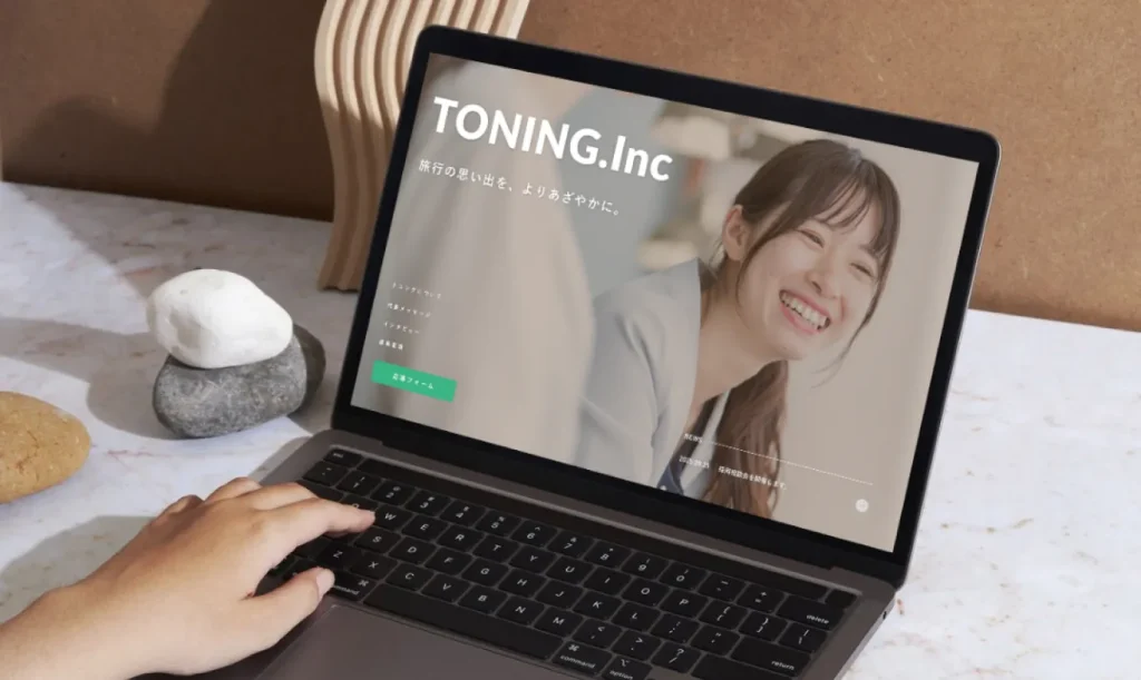 おしゃれなデスクに置かれたPCに映し出されるTONINGのwebサイト