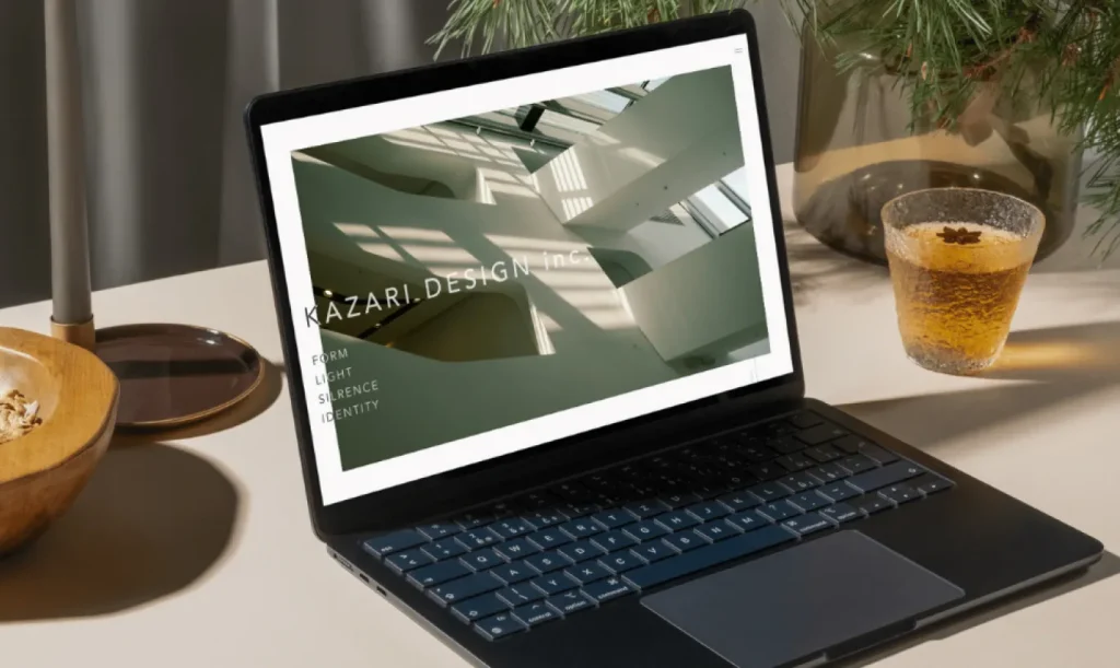 おしゃれなデスクに置かれたPCに映し出されるKAZARI DESIGNのwebサイト
